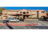 Tan apartment building with covered parking, landscaping, and parking spots at 5751 E Hacienda Ave # 172, Las Vegas, NV 89122