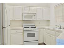 A well-lit kitchen featuring white appliances, cabinets, and countertops at 1842 Scimitar Dr # 13, Henderson, NV 89014