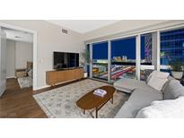 Modern living room with a gray sectional sofa, wood flooring, and a stunning city view at night at 4471 Dean Martin Dr # 2705, Las Vegas, NV 89103
