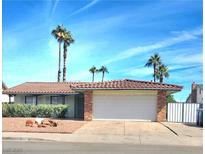 Charming single-story home with tile roof, two-car garage, and desert landscaping with mature palm trees at 4480 Annie Oakley Dr, Las Vegas, NV 89121