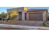 Beautiful single-story home with stone accents, a brick driveway, and a modern garage door at 51 Reflection Cove Dr, Henderson, NV 89011