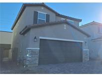 Two-story home with neutral siding and a large two-car garage with stone veneer accents at 8125 Glade Crossing Ave, Las Vegas, NV 89113