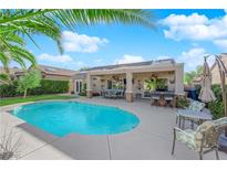 Relaxing backyard featuring a sparkling blue pool and covered patio with outdoor seating and lush greenery at 2244 Garden City Ave, Henderson, NV 89052