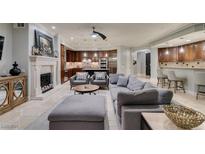 Open-concept living room showcases tile floors, gray furniture, and a stone fireplace at 30 Via Mantova # 202, Henderson, NV 89011