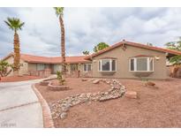 Charming single-story home with a red tile roof, desert landscaping, and a circular driveway with mature palm trees at 5990 Mcleod Dr, Las Vegas, NV 89120