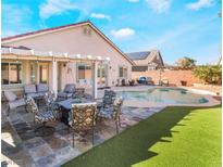 Relaxing backyard oasis featuring a sparkling pool, lush artificial grass, and a cozy outdoor seating area at 6608 Ringbill Ct, North Las Vegas, NV 89084