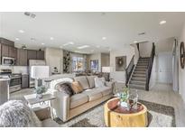 Sunlit living room with sleek tile flooring, a plush sofa, modern decor, and an adjacent dining area with backyard views at 8917 Pebble Sand St, Las Vegas, NV 89178