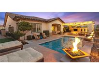 A luxurious backyard featuring a stunning pool with fire bowls and a covered outdoor living area at 12217 Tempestad Ave, Las Vegas, NV 89138