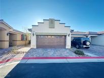 Beige home featuring a two-car garage with a brick-lined driveway and a view of the bright blue sky at 2241 Chandler Ranch Pl, Laughlin, NV 89029