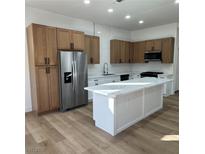 Spacious kitchen with stainless steel appliances, wood cabinets and a central island with a white countertop at 10405 Junction Hill Dr, Las Vegas, NV 89134