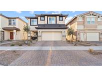 Two story home featuring a two car garage with a patterned driveway and minimalistic landscaping at 333 Canary Song Dr, Henderson, NV 89011