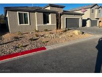 Contemporary stucco home featuring low maintenance landscaping, a gray garage door and a red-painted curb at 5230 Lissome Lily Ct, Las Vegas, NV 89139