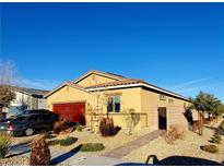 Charming single-story home with a red garage door, desert landscaping, and a blue sky above at 7910 Shimmery St, North Las Vegas, NV 89084