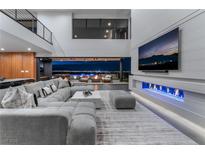Bright living room with modern fireplace, sectional sofa, and sliding doors opening to the outdoor entertaining space at 801 Dragons Eye Dr, Henderson, NV 89012