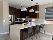 Modern kitchen featuring stainless steel appliances, dark wood cabinetry, and a stylish island with seating at 11023 Bellatrix Ct, Las Vegas, NV 89135