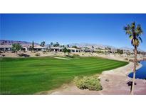 Beautiful golf course view with lush green grass and palm trees in a desert community against a mountain backdrop at 5059 Pensier St, Las Vegas, NV 89135