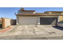 Two-car garage with a driveway needing some repair work and exterior with a stucco finish in need of some TLC at 1228 Mews Ln, Las Vegas, NV 89101