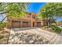 Stunning home featuring a three-car garage, beautiful stone accents, and a well-manicured front yard with mature trees at 409 Lake Windemere St, Las Vegas, NV 89138