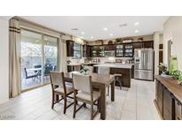 Bright, open kitchen featuring stainless steel appliances, dark cabinetry, and a dining area with sliding glass doors at 8992 Sparkling River Ct, Las Vegas, NV 89178