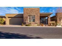Charming single-story home featuring a stone facade, manicured landscaping, and a two-car garage at 9858 Gemstone Sunset Ave, Las Vegas, NV 89148
