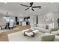 Open-concept living room flows to dining and kitchen with light wood floors and a modern ceiling fan at 4578 Ridgedale Ave, Las Vegas, NV 89121