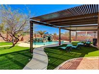 Inviting backyard oasis with a sparkling pool, rock waterfall, pergola, and comfortable lounge seating on lush artificial turf at 6689 Sparks Ave, Las Vegas, NV 89142