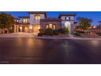 Elegant two-story home with stone accents, meticulously landscaped yard, and a spacious two-car garage at twilight at 10008 Peak Lookout St, Las Vegas, NV 89178