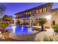 A backyard pool is surrounded by palm trees, rock features, and a seating area, creating a serene oasis at 10008 Peak Lookout St, Las Vegas, NV 89178