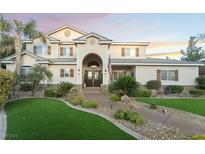 Beautiful two-story home featuring a manicured lawn, an arched entrance, and lovely landscaping at 7600 Pleasant Colony Ct, Las Vegas, NV 89131