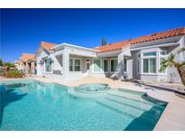 Inviting backyard pool with a spa, steps, and tile trim surrounded by lush desert landscaping and stucco walls at 2265 Lauren Dr, Las Vegas, NV 89134