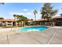 Community pool surrounded by palm trees and buildings, perfect for relaxation and outdoor enjoyment at 2606 S Durango Dr # 276, Las Vegas, NV 89117