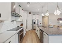 Bright kitchen features stainless steel appliances, hardwood floors, pendant lighting, and white cabinetry at 3018 Fall Solstice Ct, Las Vegas, NV 89138