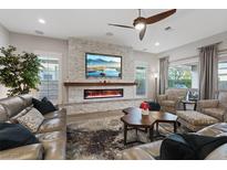 Inviting living room with stone fireplace, sleek TV, ceiling fan, and comfortable seating arrangement at 3018 Fall Solstice Ct, Las Vegas, NV 89138