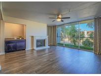 Bright living room featuring hardwood floors, fireplace, and a large window with natural light at 725 N Royal Crest Cir # 213, Las Vegas, NV 89169