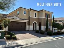 Two story tan home with tile roof, landscaping, and a multi-gen suite at 945 Pomander Point Pl, Henderson, NV 89012