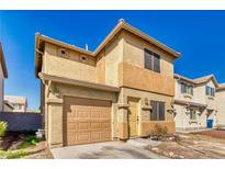 Two-story home features a tan stucco exterior, garage, and well-lit front entrance, creating a welcoming curb appeal at 5179 Floralita St, Las Vegas, NV 89122