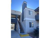 Two-story condo building with stucco exterior, gray accents, and stairs to the second level at 8600 W Charleston Blvd # 2195, Las Vegas, NV 89117