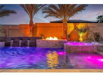 Stunning pool with water features, spa, and fire pit, surrounded by lush landscaping and ambient lighting at 9091 Becket Ranch Ct, Las Vegas, NV 89113