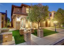 Charming two-story home featuring a well-manicured front yard and inviting entrance with decorative brick pillars and lovely tree at 1272 Olivia Pkwy, Henderson, NV 89011