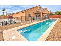 A sparkling in-ground swimming pool with a safety fence in the backyard with desert landscaping at 172 Turtle Ridge Ave, Las Vegas, NV 89183