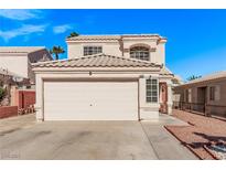Two-story home featuring a well-maintained front yard with xeriscape, a two-car garage, and a beige exterior at 8068 Cetus Cir, Las Vegas, NV 89128