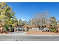 Charming single-story home featuring a well-manicured front yard with mature trees and desert landscaping at 976 El Camino Way, Boulder City, NV 89005