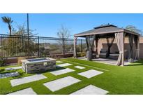 Inviting backyard with a stone fire pit, stylish gazebo, and lush artificial grass at 59 Strada Loreto, Henderson, NV 89011