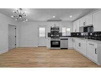 Bright kitchen features white cabinets, stainless steel appliances, and black tiled backsplash at 2512 Taylor Ave, North Las Vegas, NV 89030