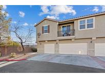 Three-story townhome featuring a balcony, three garage doors, and neutral color palette at 4305 Morgan Manor St # 3, North Las Vegas, NV 89032