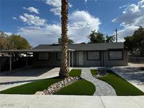 Charming home featuring a well-maintained yard, complemented by a lush green lawn and complemented by desert landscaping at 6117 Iris Cir, Las Vegas, NV 89107