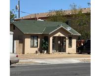 Charming single-story home featuring tan stucco and a vibrant green roof with security bars on the front porch at 315 N 9Th St, Las Vegas, NV 89101