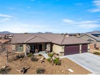 Charming single-story home featuring a three-car garage, desert landscaping, and a welcoming front porch at 150 Spruce Ln, Pahrump, NV 89048