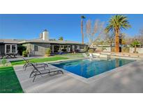 Inviting backyard pool with modern lounge chairs and green grass, perfect for relaxing and entertaining at 2711 Ashby Ave, Las Vegas, NV 89102