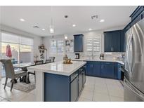 Modern kitchen features navy cabinets, stainless appliances, and a large center island with counter seating at 4733 Cactus Sun Ln, North Las Vegas, NV 89031